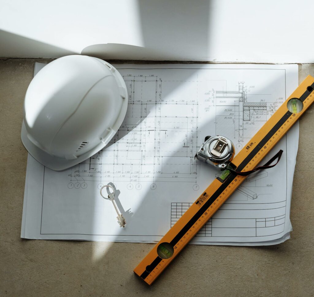 Top view of architectural blueprint with helmet and tools on table, ideal for construction theme.